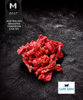 A pile of sliced raw beef stir fry pieces on a dark textured background, with a black label reading 'BEEF AUSTRALIAN GRASSFED TENDEROIN STIR FRY' and a Cape Grim Beef logo in the bottom right corner.