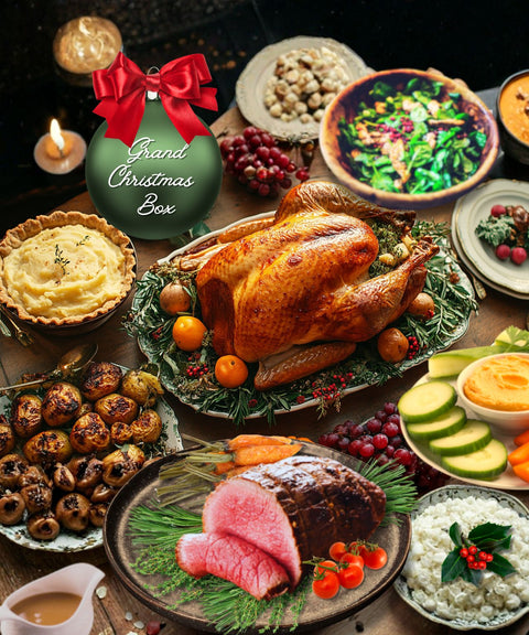 Assorted holiday dishes including a turkey, beef, and various side dishes on a wooden table with a 'Grand Christmas Box' ornament.
