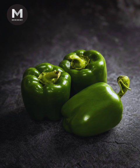 Three pieces of green capsicum on a dark background