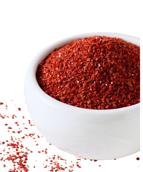 White bowl filled with loose chili flakes on a white background