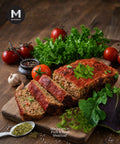 Sliced Marjoram meatloaf on a wooden board with fresh vegetables and herbs.