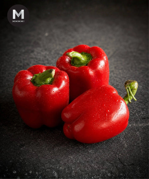 Three red capsicum on a dark backrground