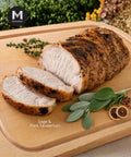 Sliced pork tenderloin on a wooden cutting board with sage, featuring the brand 'Mmmm'.