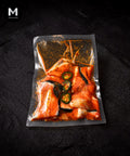 Vacuum-packed NZ King Salmon bones marinated in Cajun spice blend with jalapeño slices, on black background