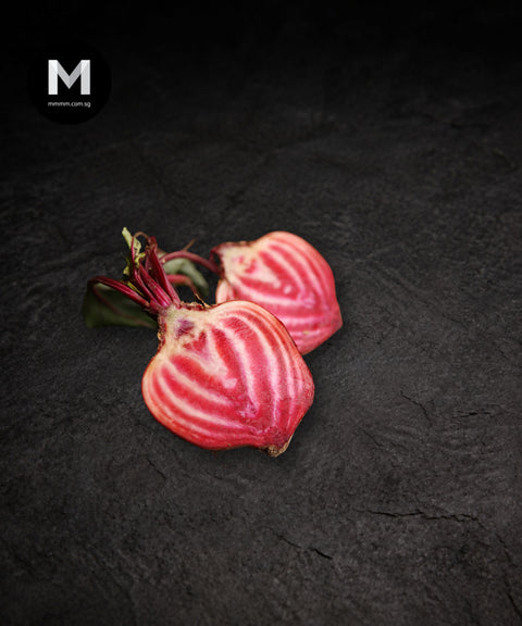 Candy cane (Chioggia) beets sliced, showing pink and white ring pattern, on a black background