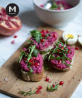 Beetroot hummus on toasted bread with arugula and pomegranate