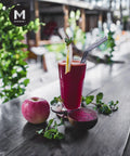 Fresh beetroot juice in a glass with apple and mint garnish