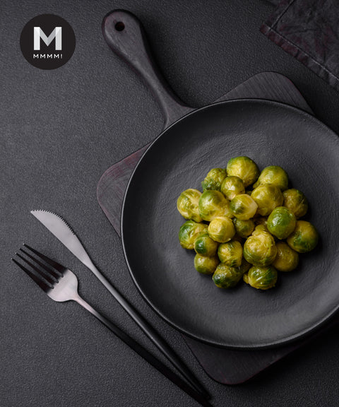 Cooked brussels sprouts served on a black plate