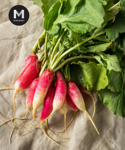 Bunch of breakfast radishes with leaves, styled on linen cloth